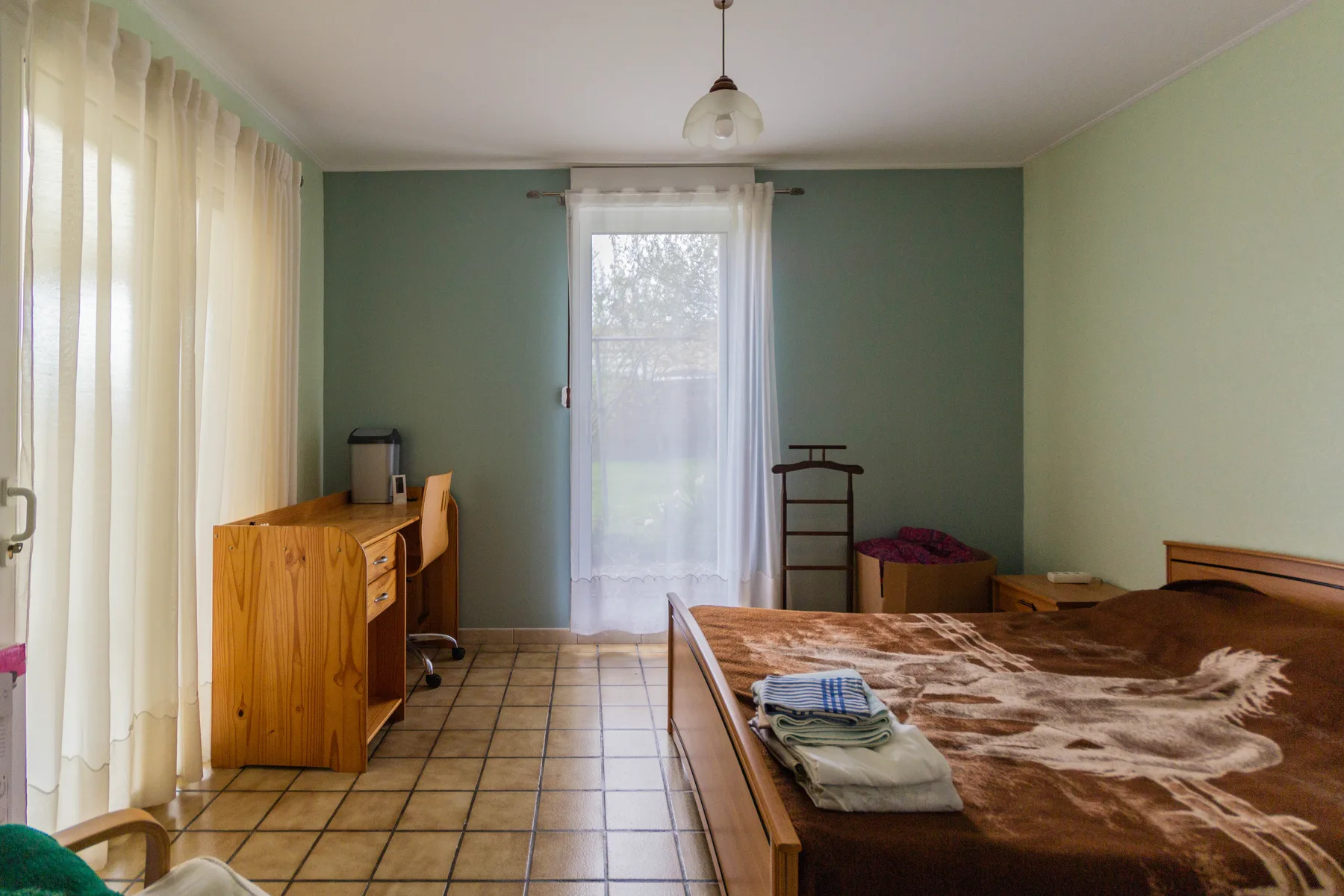 Chambre avant rénovation avec murs verts, ancien carrelage et mobilier bois
