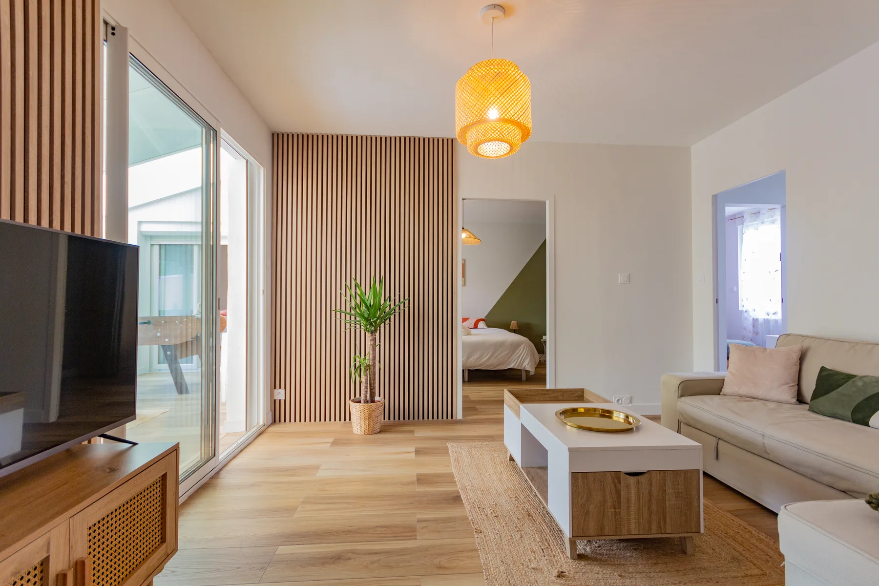 Pièce de vie après rénovation avec sol bois, mur tasseaux et décoration contemporaine