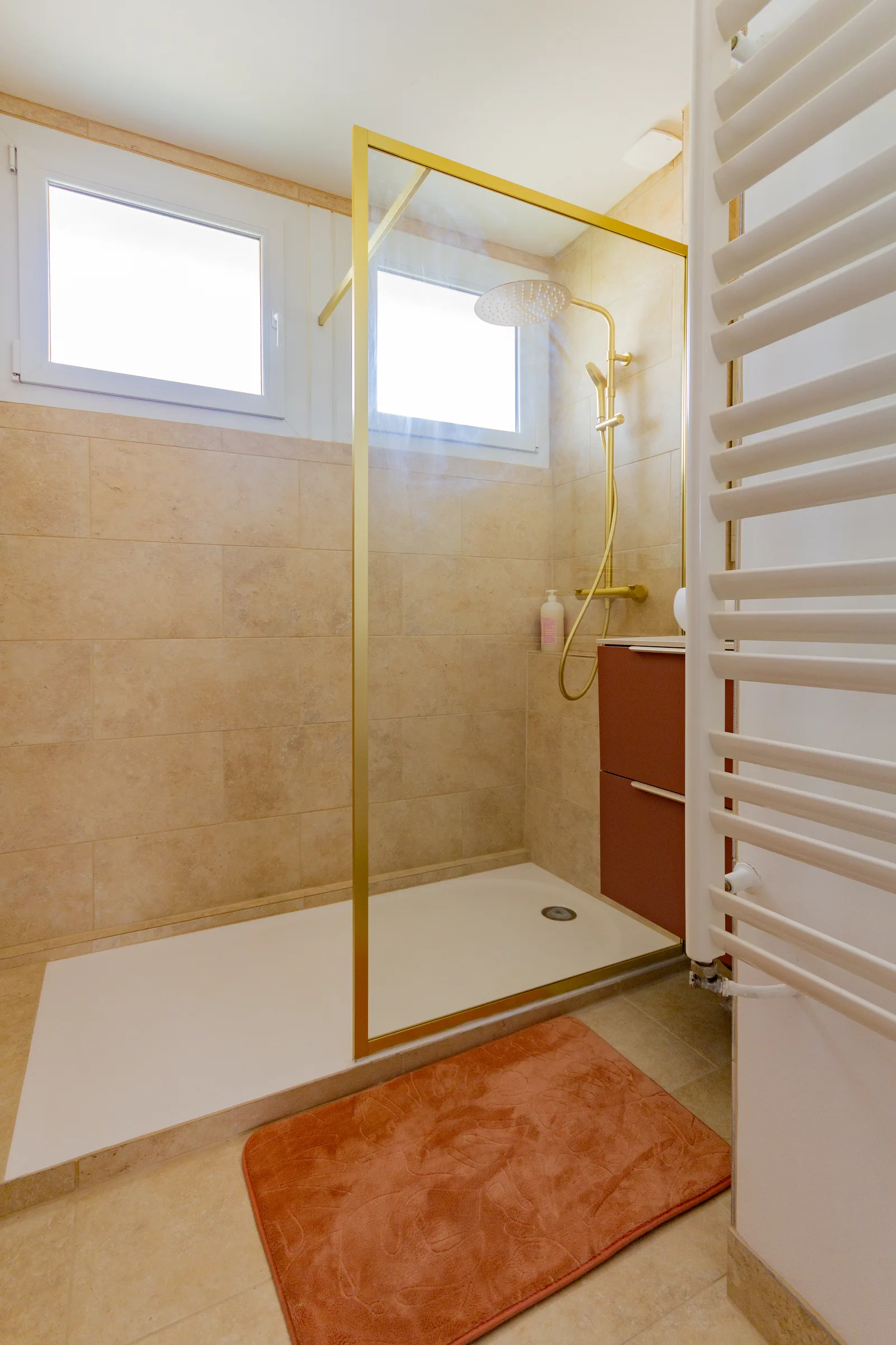 Salle d'eau après intervention avec douche ouverte, paroi dorée et finitions carrelées