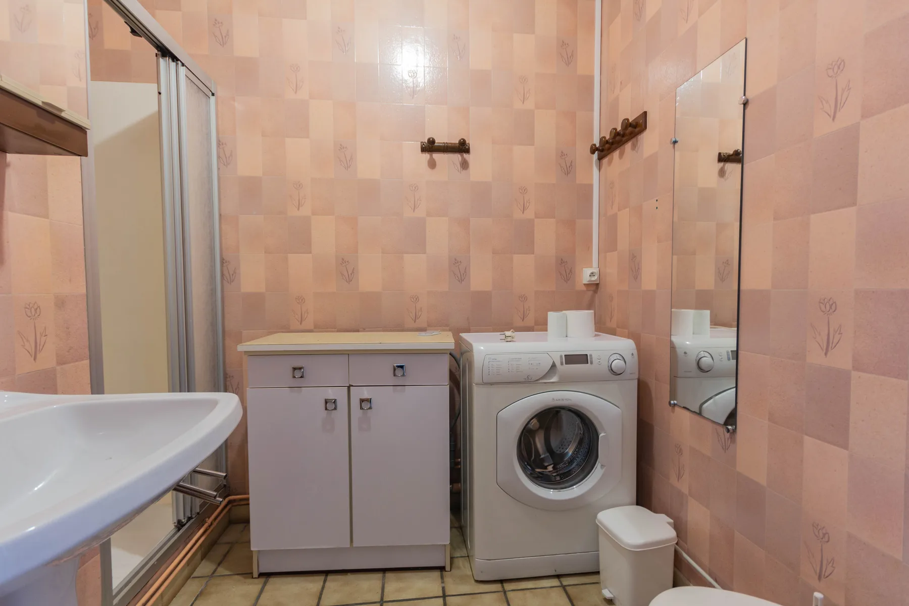 Salle d'eau avant rénovation avec anciens revêtements roses, meuble vasque et machine à laver